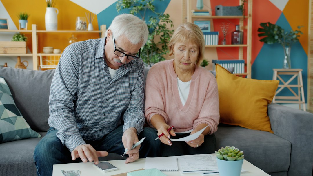 Couple de seniors consultant des documents à domicile, illustration de la préparation d’un projet de vente en viager.